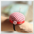Red check wrist pin cushion on a sewing table