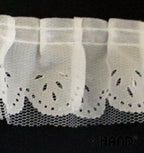 Roll of decorative white nylon ruffle trim on a flat surface