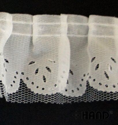 Roll of decorative white nylon ruffle trim on a flat surface