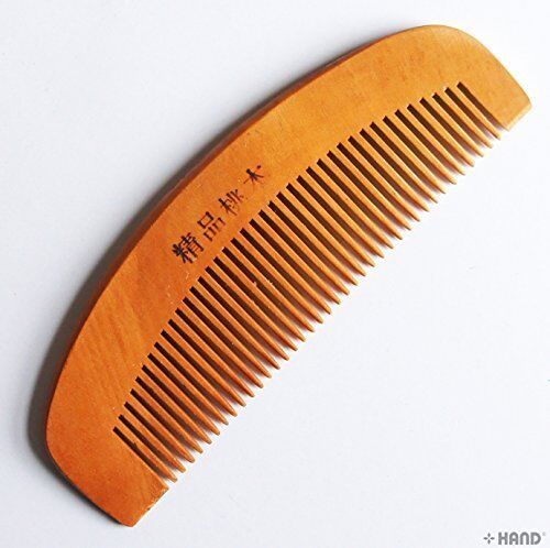 Close-up of a natural peach wood comb showing its smooth finish.