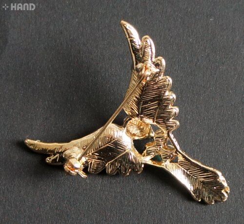 Close-up of a clear crystal bird brooch with gold detailing