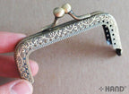 Close-up of the kiss clasp lock on the coin purse frame.