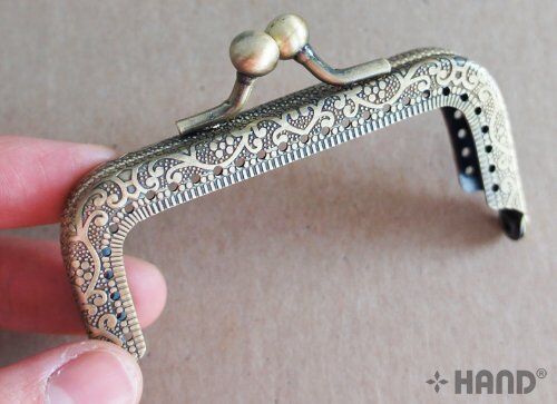Close-up of the kiss clasp lock on the coin purse frame.