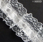 Roll of 10 metre white nylon ribbon lace trim on a table.