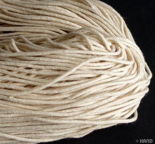 Cream thin string rope cord displayed on a wooden surface