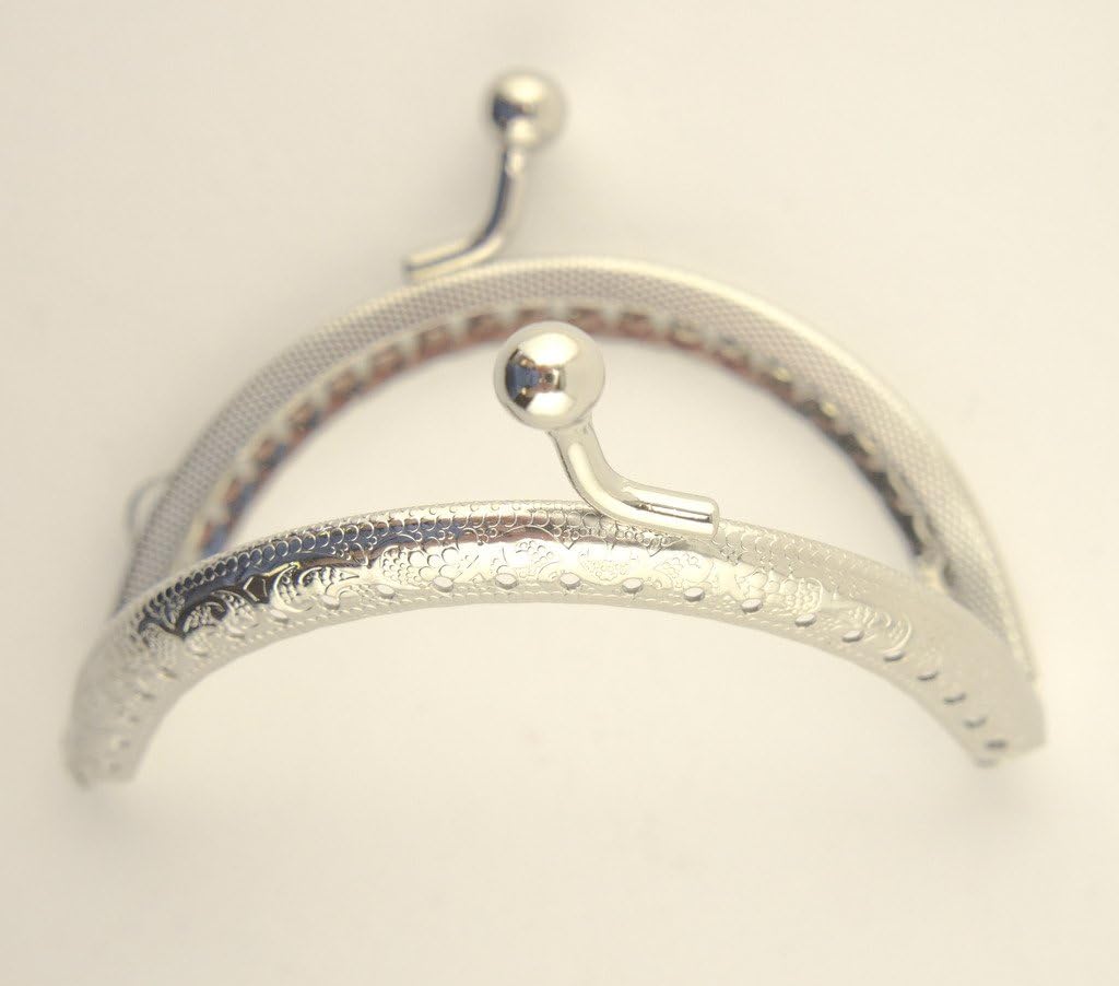 Close-up of the kiss clasp lock on the silver tone purse frame.