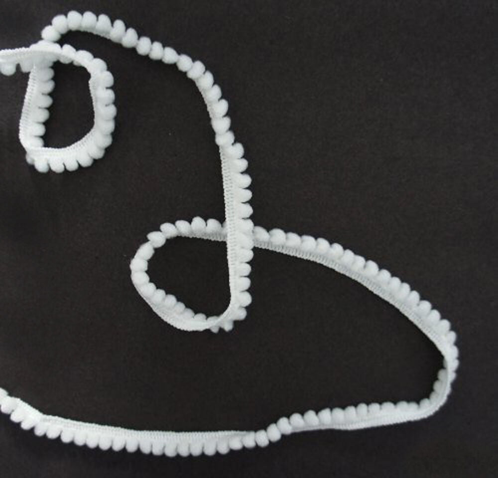 Little white pom pom trim displayed on a craft table