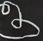 Little white pom pom trim displayed on a craft table