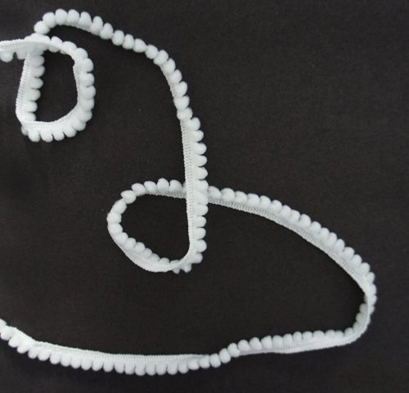 Little white pom pom trim displayed on a craft table