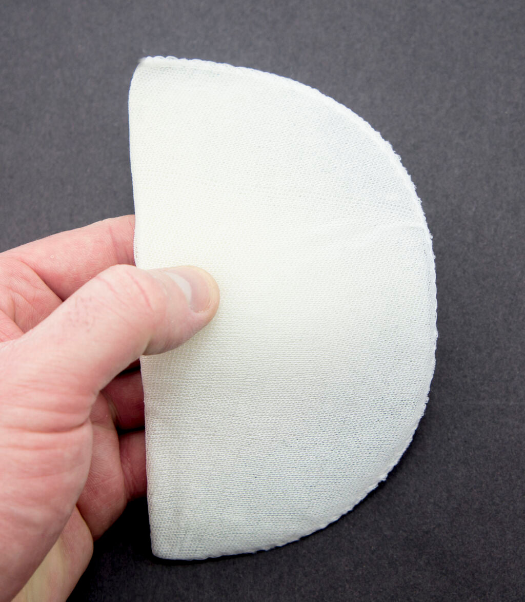 Side view of a white shoulder pad showing its shape.