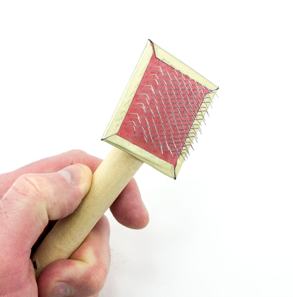 Close-up of the fur care brush showing its ergonomic handle
