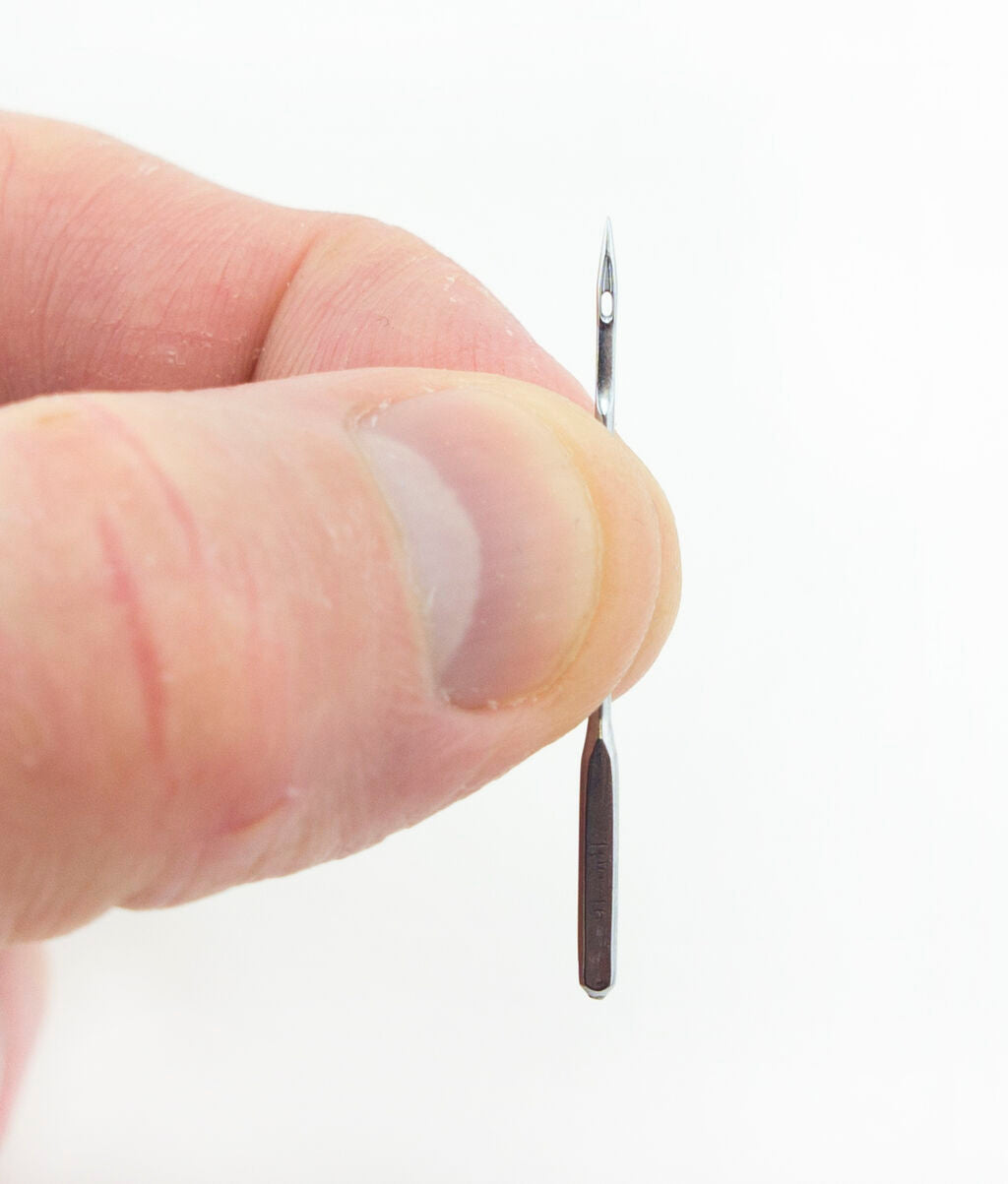 Sewing machine needles displayed on a fabric background