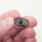 Close-up of a dark gunmetal tone button showing its 23 mm diameter.