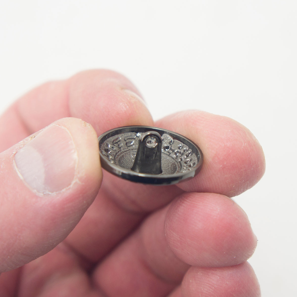 Close-up of a dark gunmetal tone button showing its 23 mm diameter.