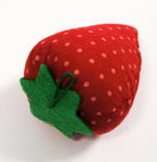 Strawberry pin cushions displayed in a sewing basket.