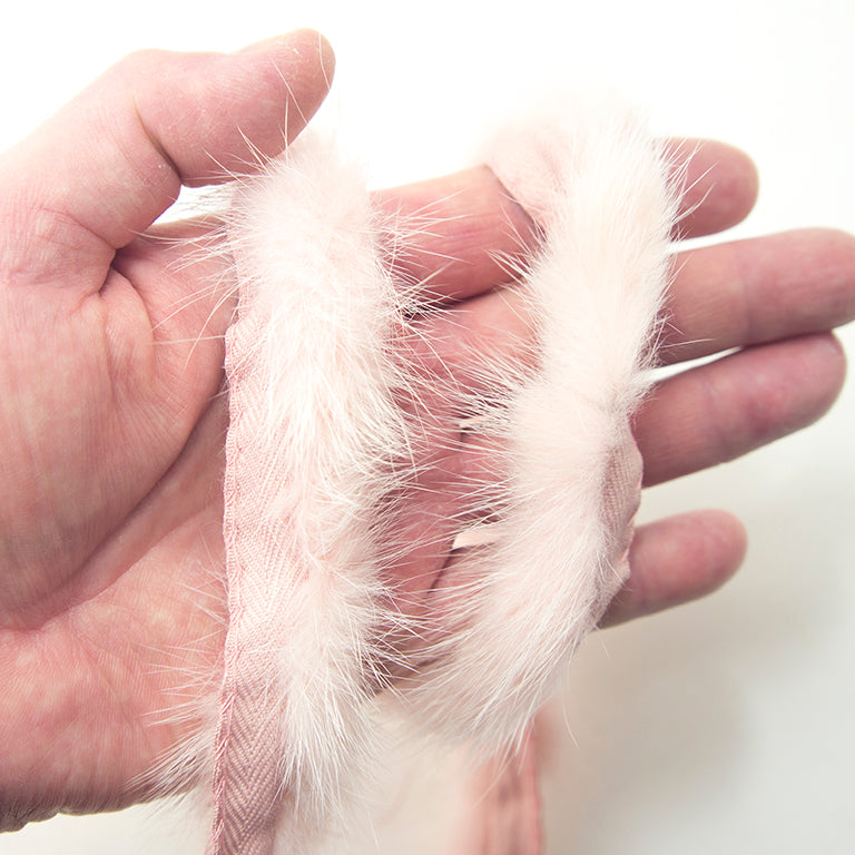 Close-up of baby pink mink sew in pipe trim on a fabric surface.