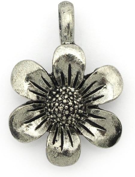 Silver flower pendant displayed with sewing accessories.