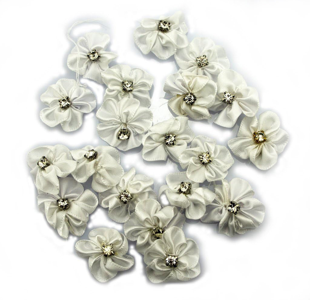 Display of white satin ribbon and diamante flower trims on a table