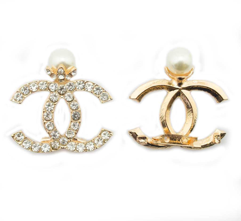 Close-up of a gold brooch with diamante crystals and safety pin.