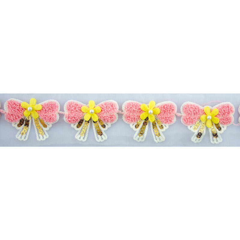 Close-up of pink bow and yellow flower decorative trim on net backing.