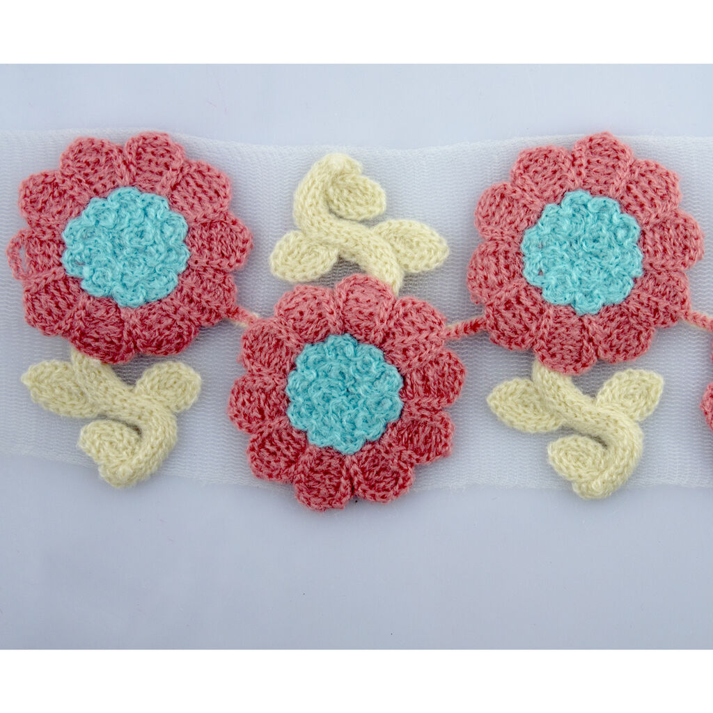 Close-up of knitted flower trim showing pink and blue design