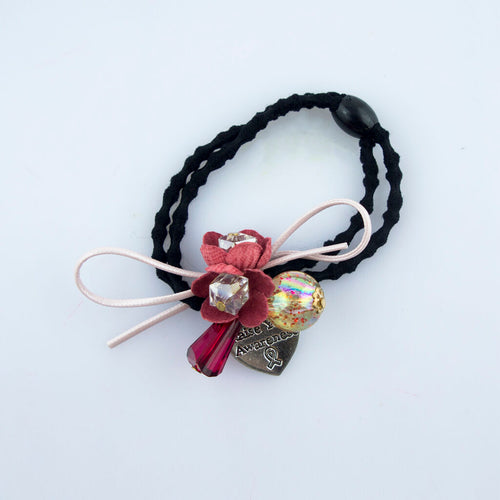 Close-up of a black hairband featuring a silver tone charm.
