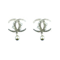 A pair of elegant brooches with white crystals and pearl beads in a silver tone metal setting.