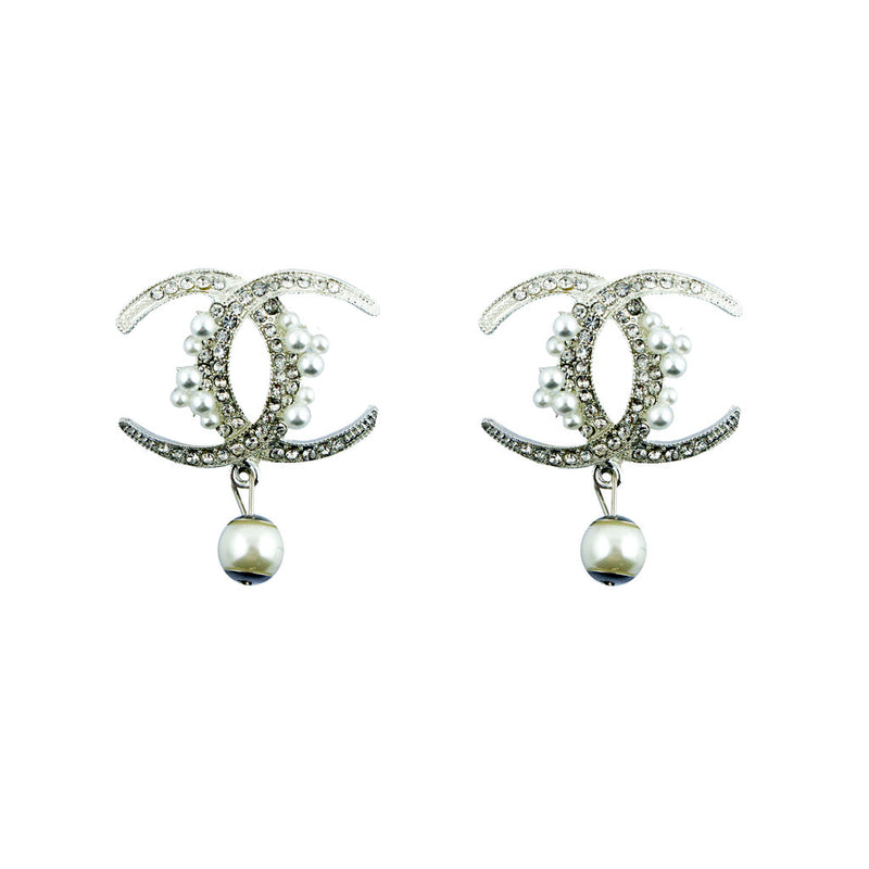 A pair of elegant brooches with white crystals and pearl beads in a silver tone metal setting.