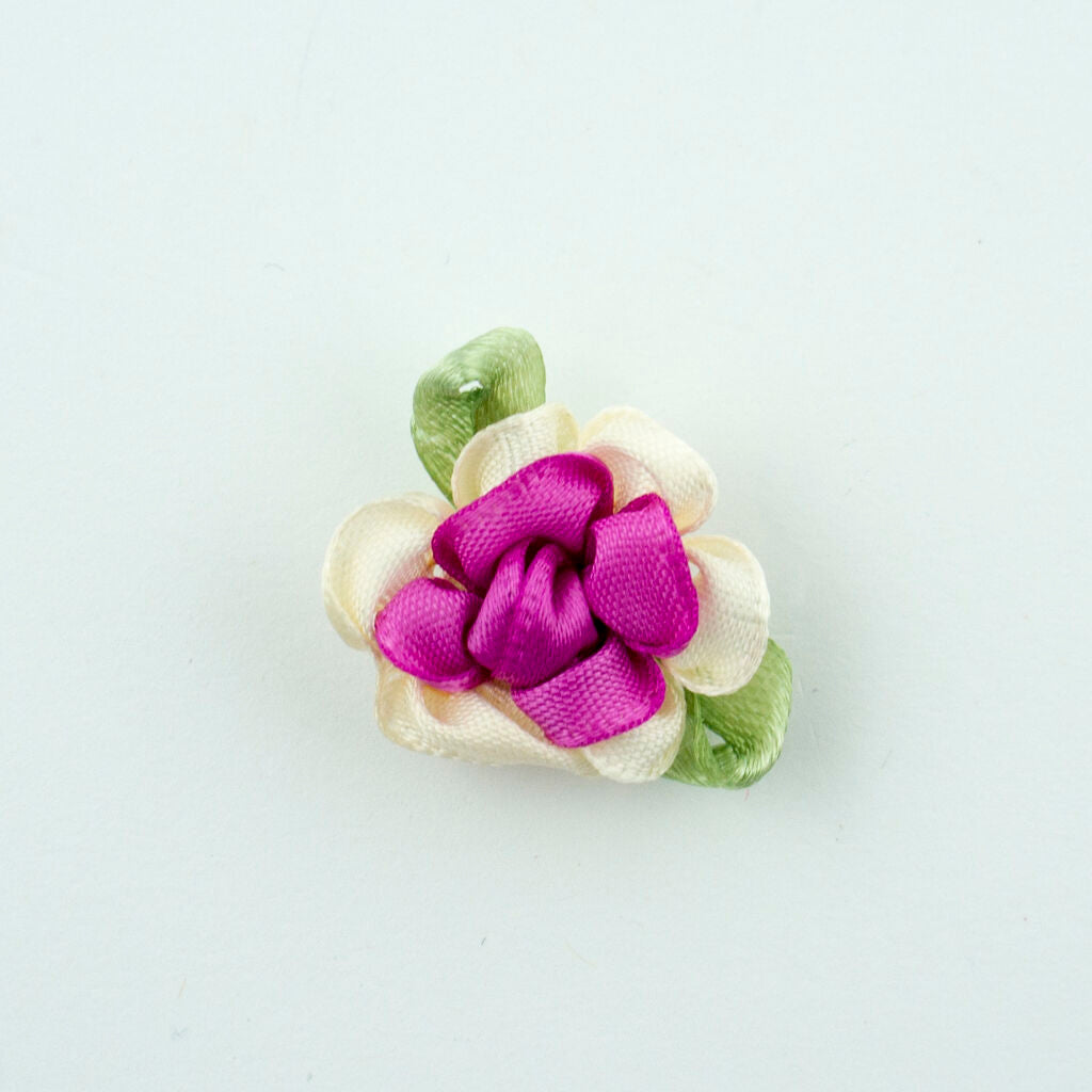 Close-up of a ribbon flower trim with green leaf detail.