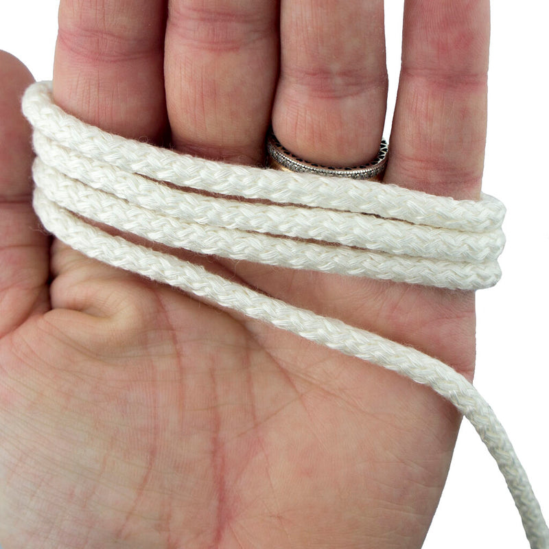 Off white silky rope trim with solid core displayed on a spool.