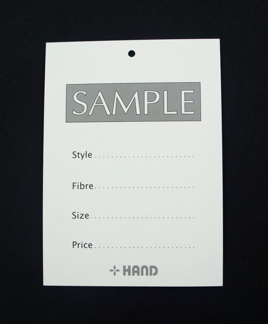 Close-up of garment sample card showing style, fibre, size, and price fields.
