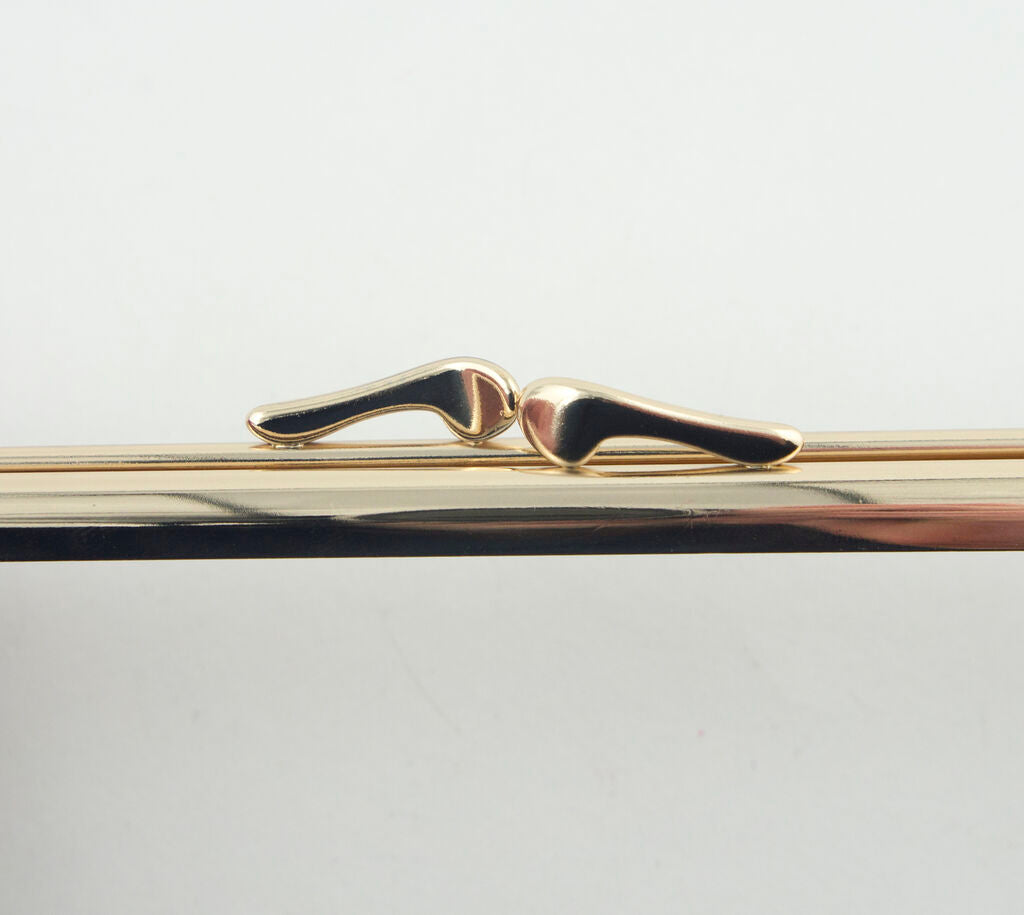 Stylish gold tone slim square purse frame displayed on fabric.