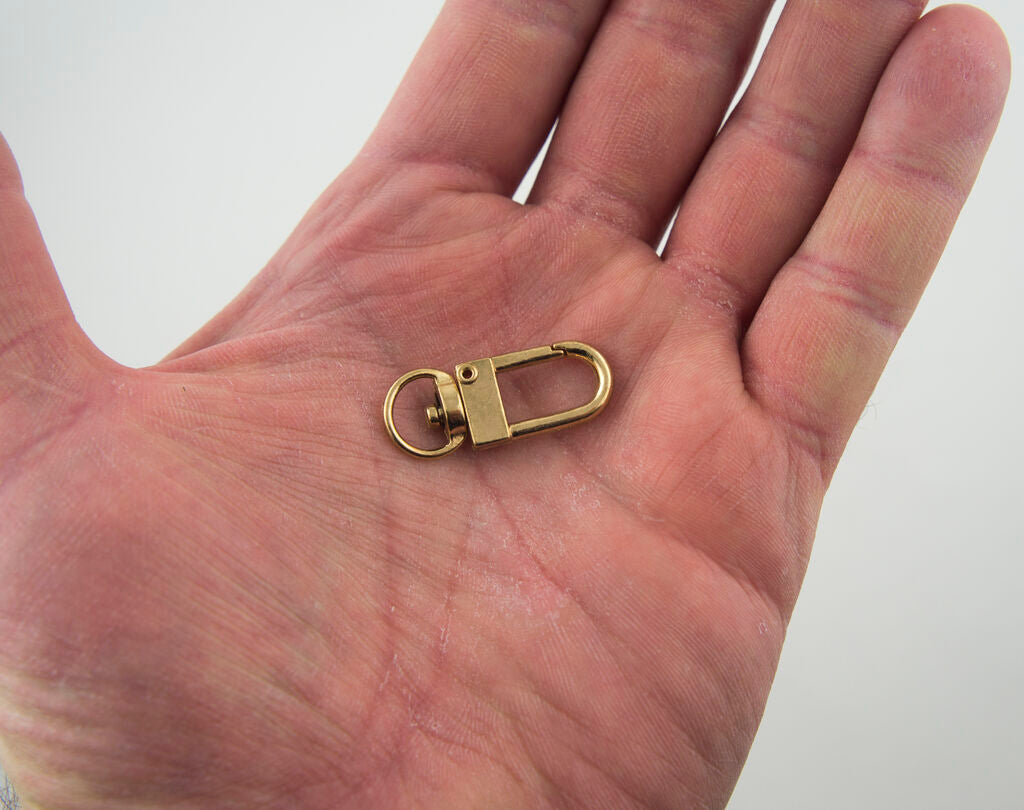 Close-up of a gold tone metal snap hook clasp and swivel ring.