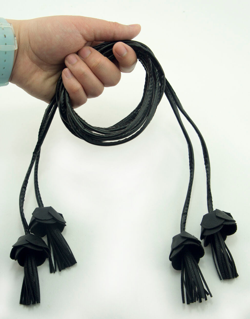 Close-up of flower tassel ends on black leatherette cords.