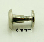 Binding screws in use, securing papers and fabric samples together.