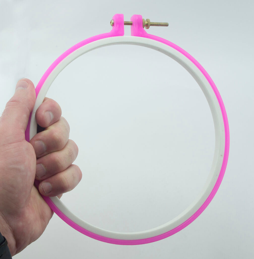 Pink embroidery hoop displayed with cross-stitch fabric.