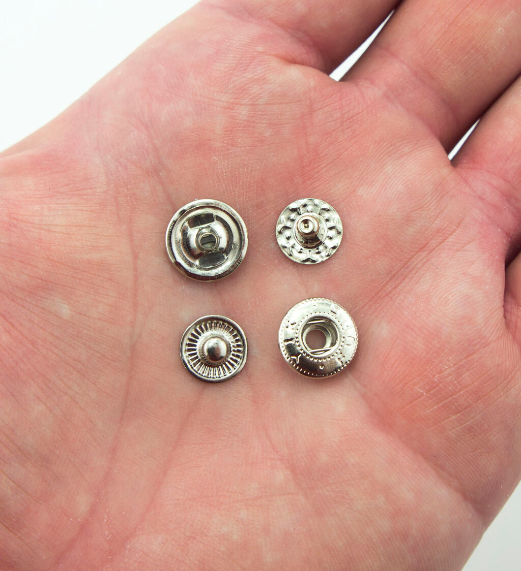 Flat lay of 12 mm diameter silver tone press stud buttons with sewing tools.
