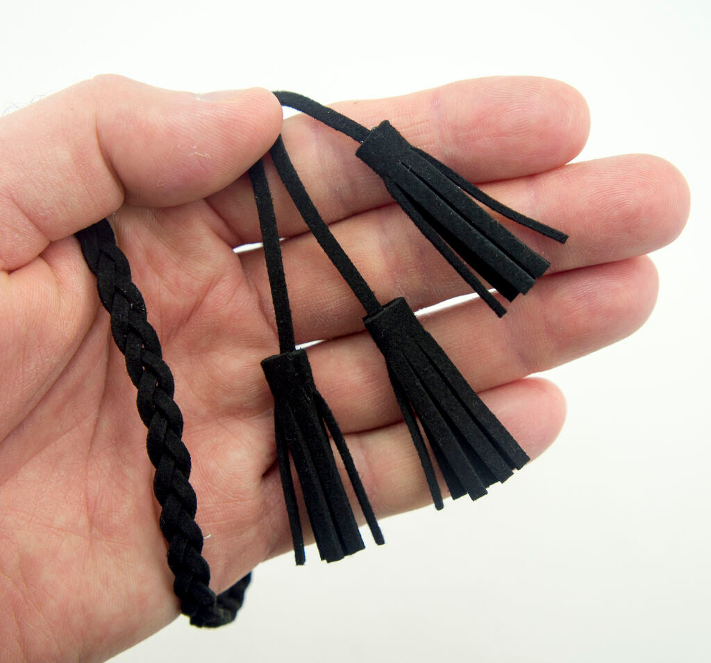 Black suede belt displayed on a garment for embellishment.