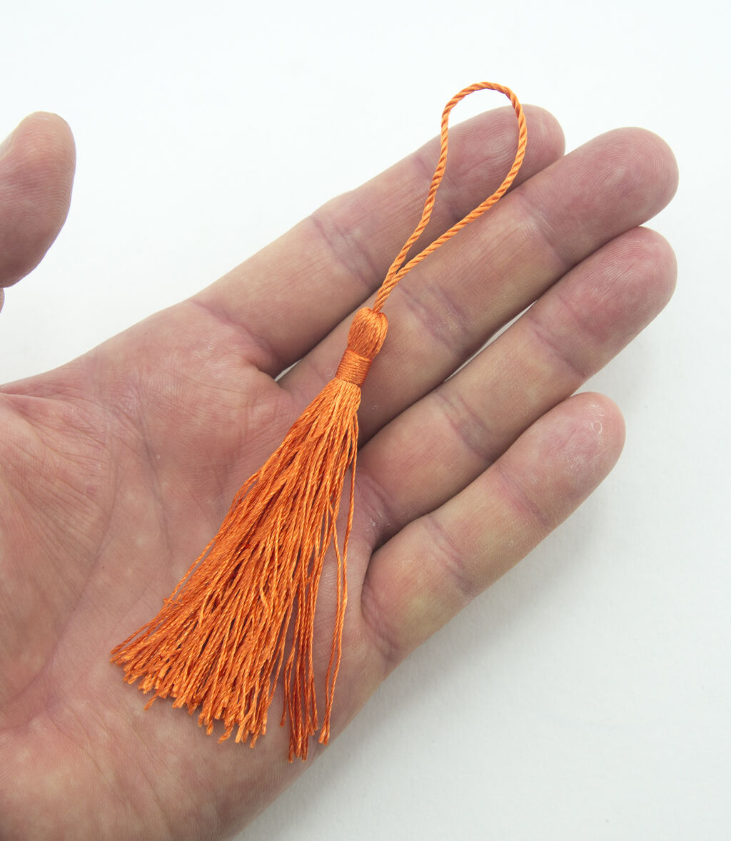 Close-up of a dark orange silky tassel, ideal for craft projects.