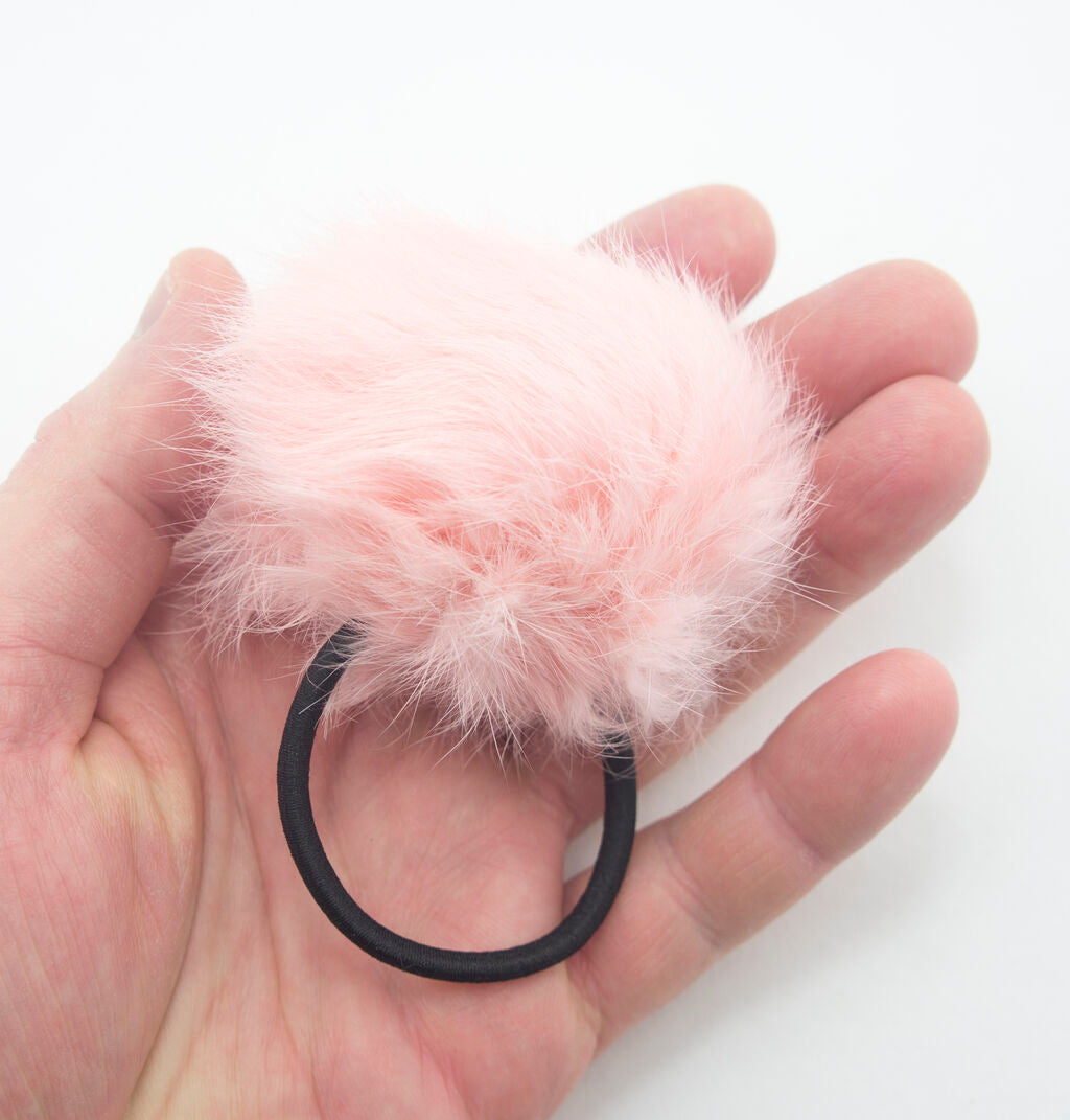 Close-up of a baby pink pom pom hair band showing the 2.5 inch loop.