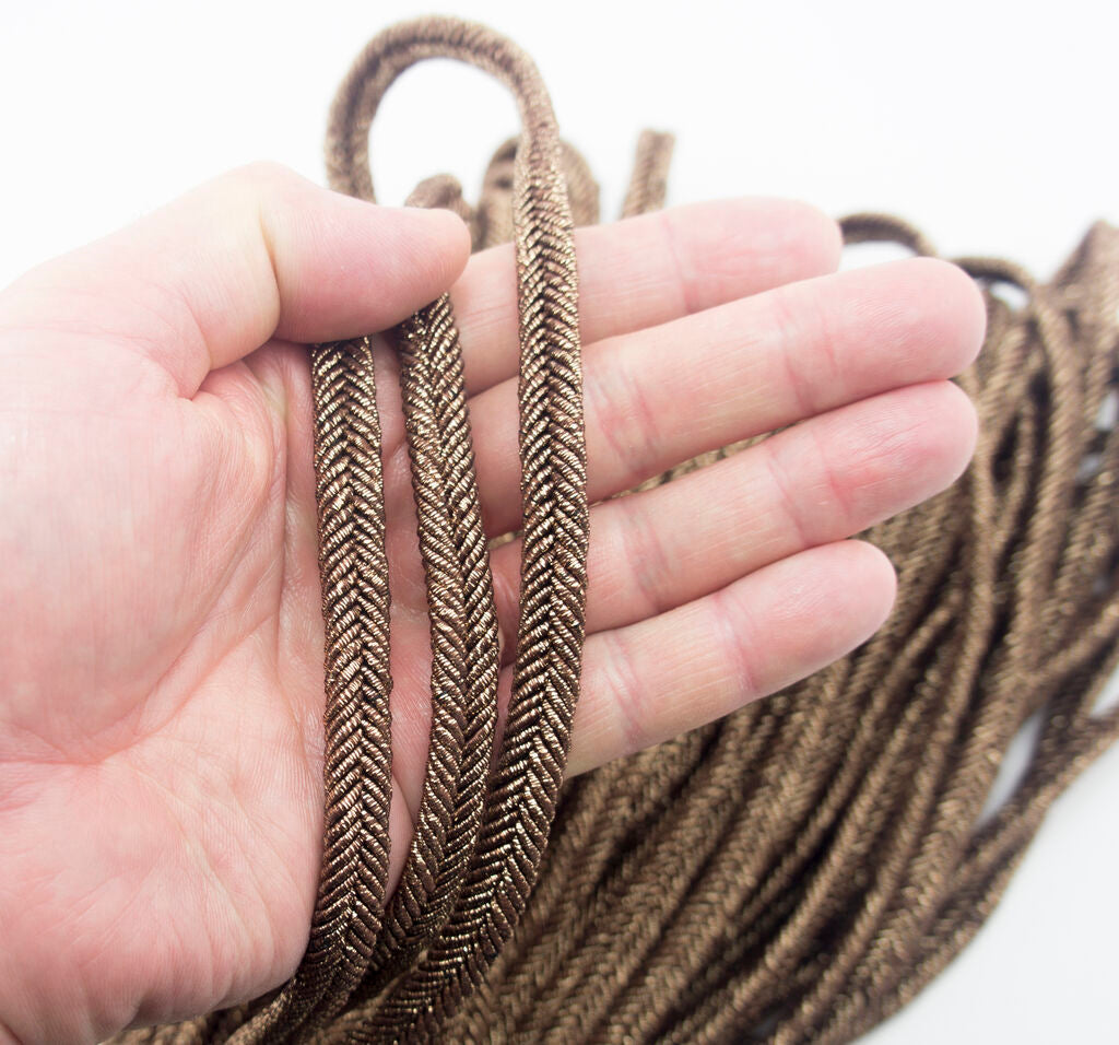 Metallic bronze plait cord trim used on a decorative garment.