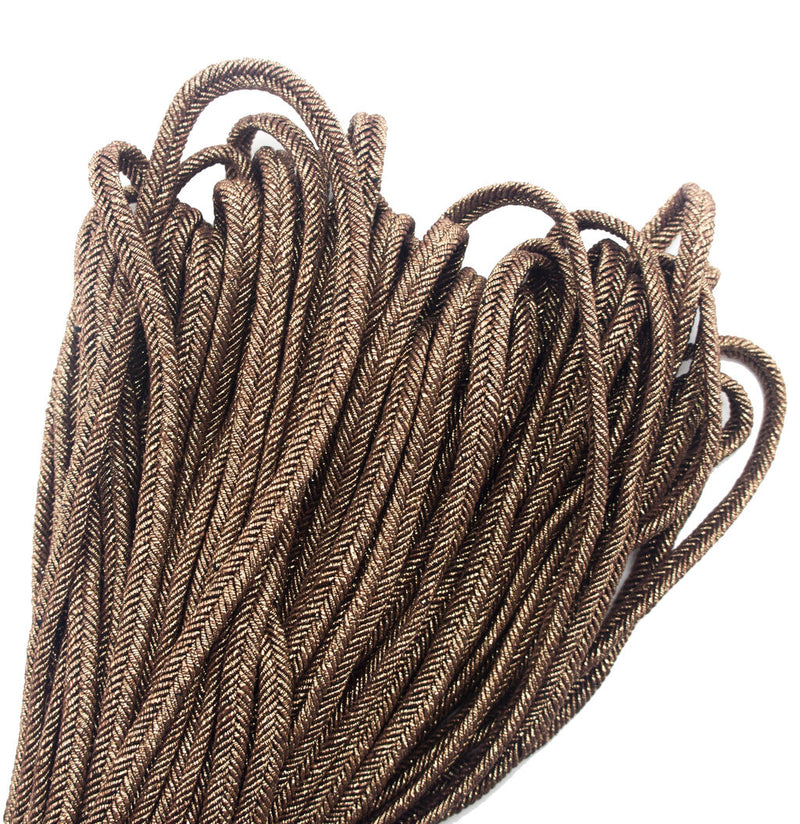 Close-up of metallic bronze plait cord trim on a white background.