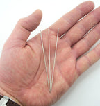 Close-up of a long steel sewing needle showing the 5.5mm eye.