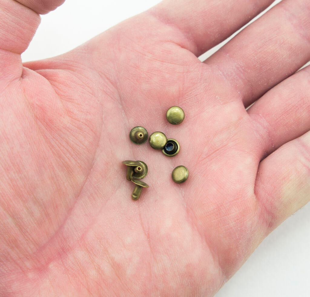 Close-up of 5 mm dark brass tone press studs for sewing projects.