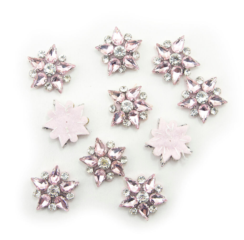 Five-point pink crystal glass star embellishments on a white background.