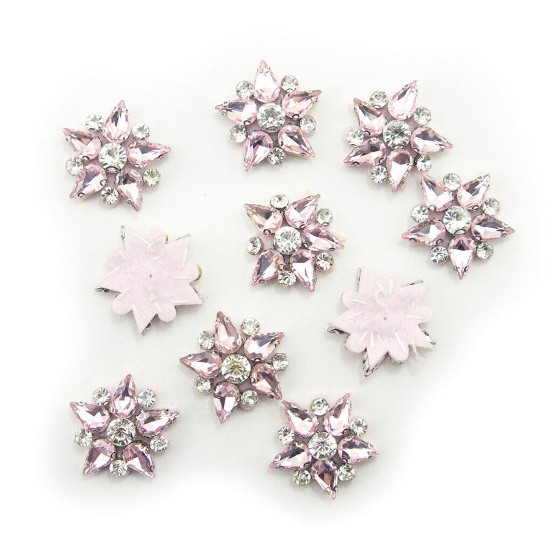 Five-point pink crystal glass star embellishments on a white background.