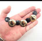 Set of 2 gold tone and black circular discs pendant chains arranged together.