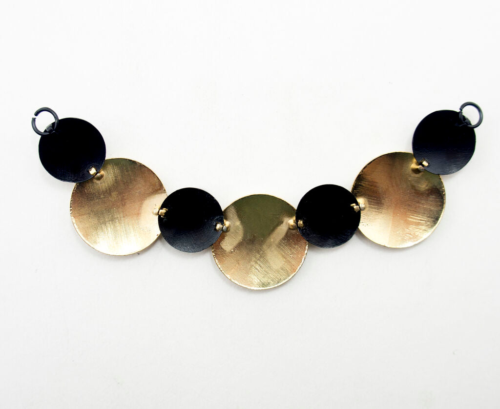 Close-up of the embossed gold tone and black discs on the pendant chain.