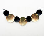 Close-up of the embossed gold tone and black discs on the pendant chain.