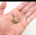 Three gold tone angel wings pendants arranged together.